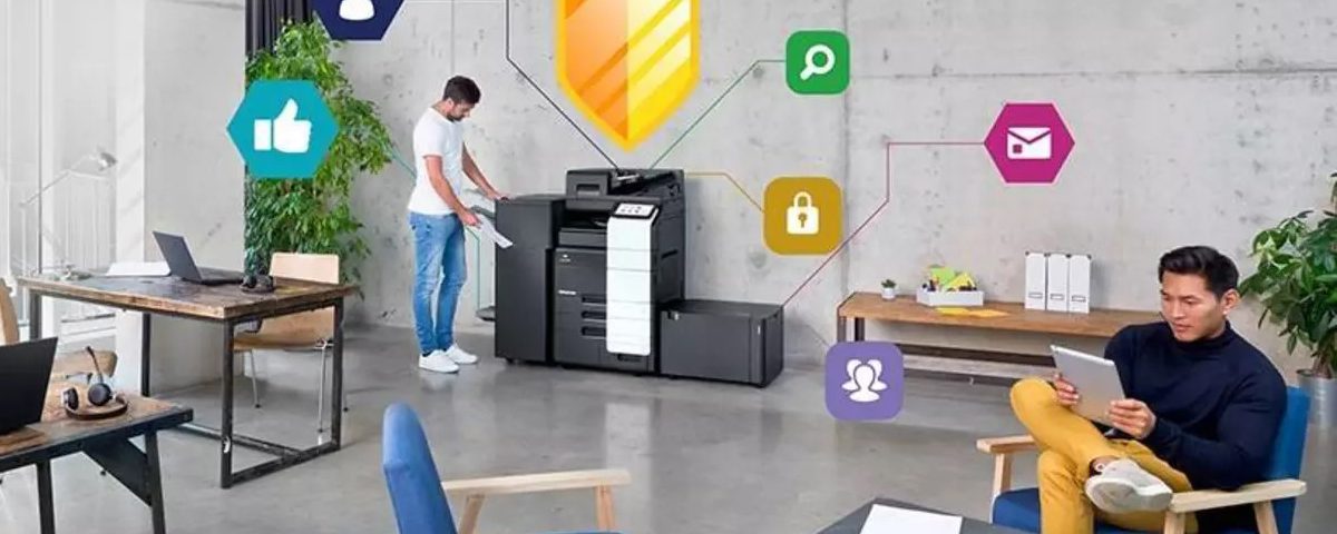 Ufficio moderno con uomo che usa una stampante multifunzione mentre un altro legge su tablet, con icone digitali di sicurezza e comunicazione intorno.
